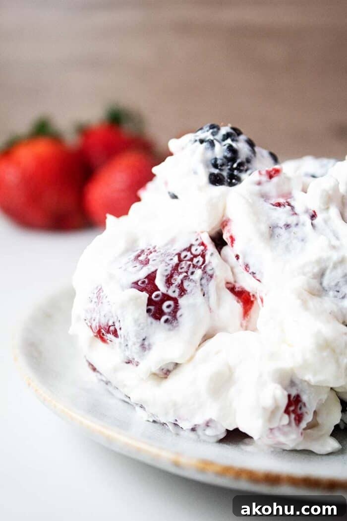 sideview of healthy keto cheesecake fluff on a white serving dish with strawberries in the background