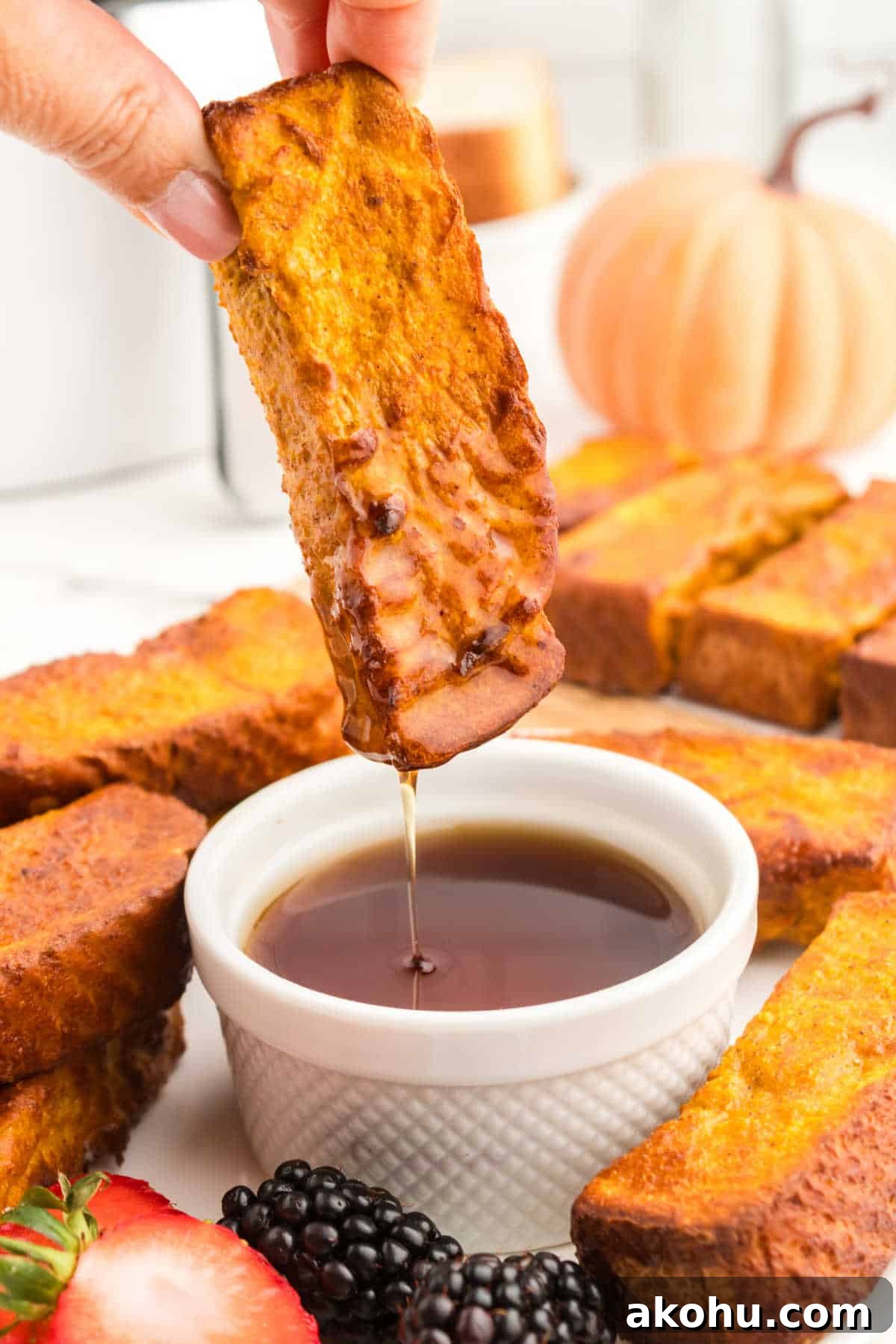 A hand dipping the recipe in maple syrup.