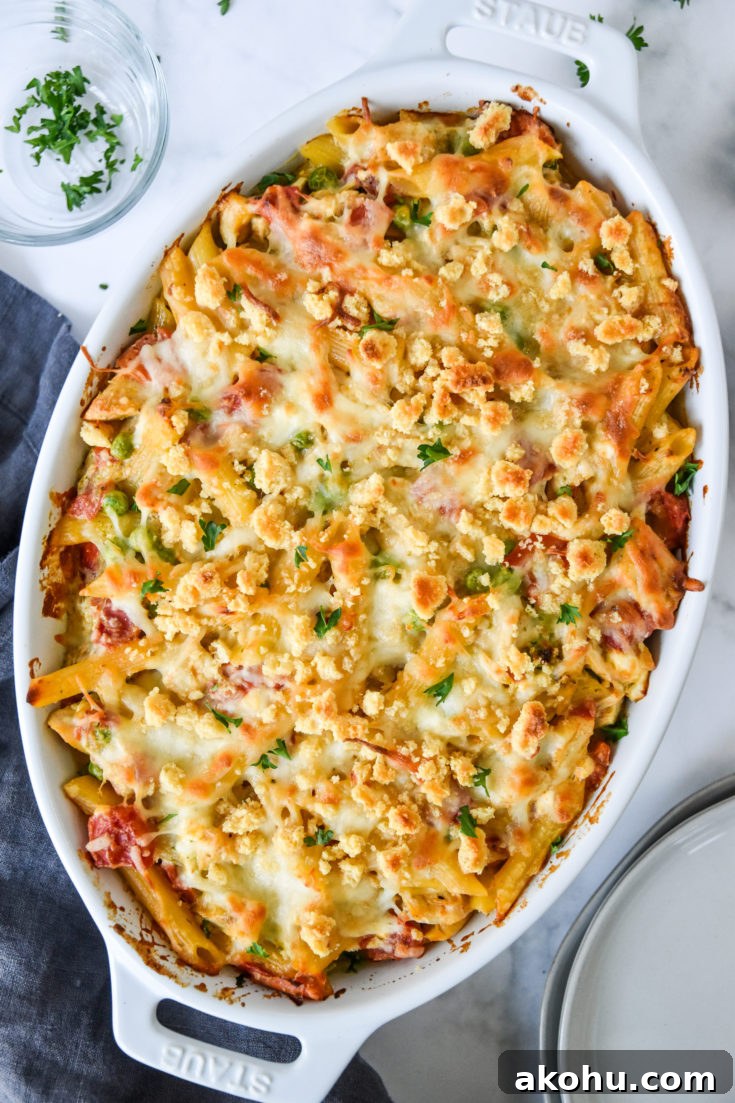 creamy pesto pasta chicken bake fresh from the oven in a white baking dish.