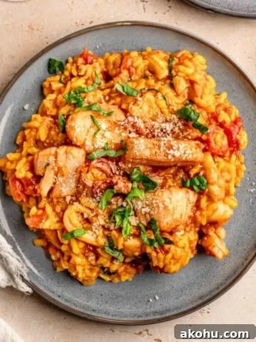 Seafood risotto topped with chopped basil on a plate.
