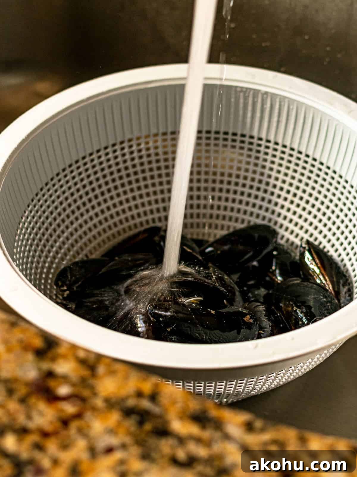 Mussels being rinsed under water in a sink.