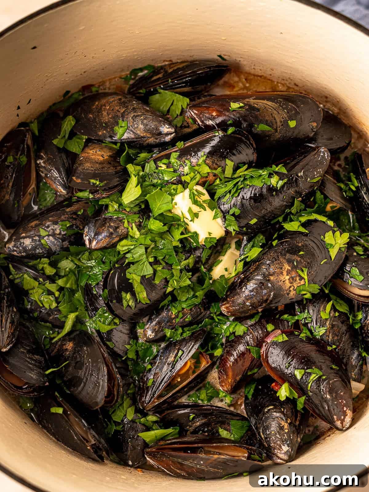 Chopped parsley on top of mussels in a pot.