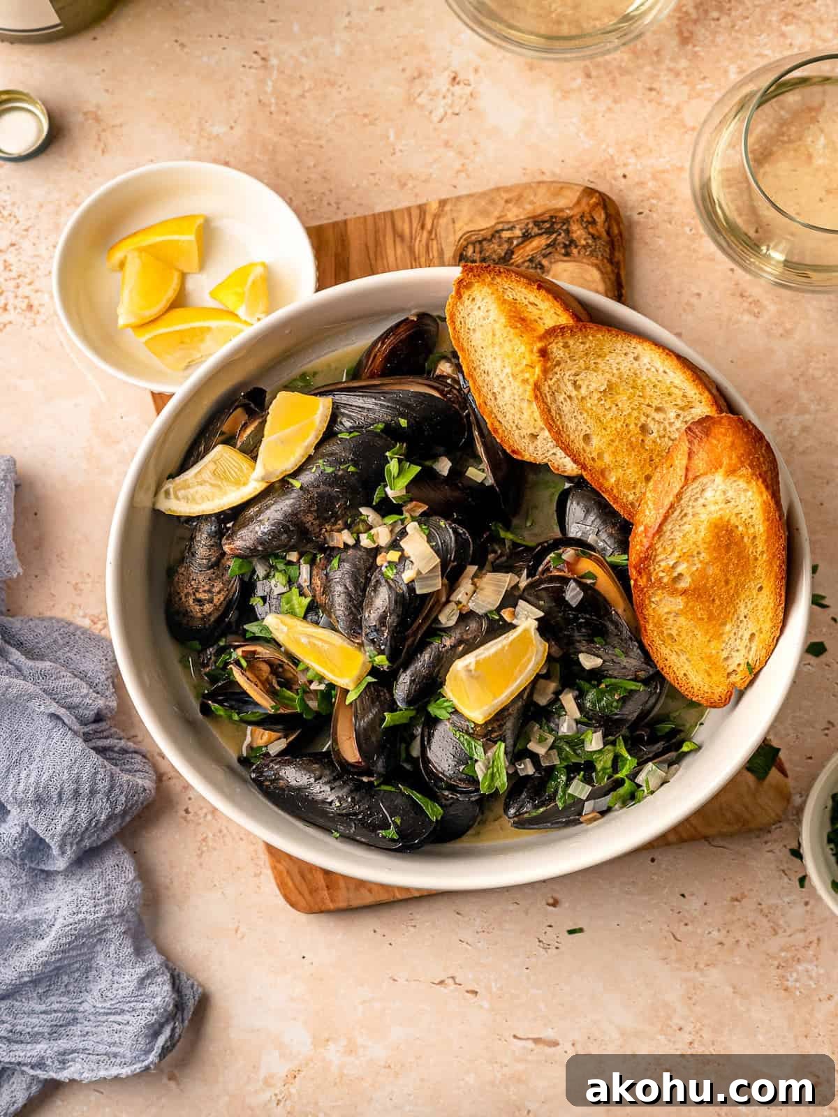 Mussels in a bowl with lemon wedges and toasted bread.
