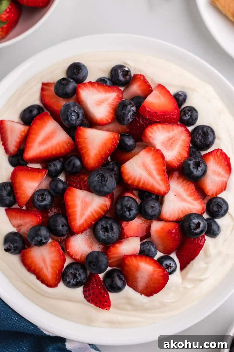 Patriotic Layered Cheesecake Dip for Fourth of July Parties 7 adding the strawberries and blueberries to the Patriotic Cheesecake Dip.