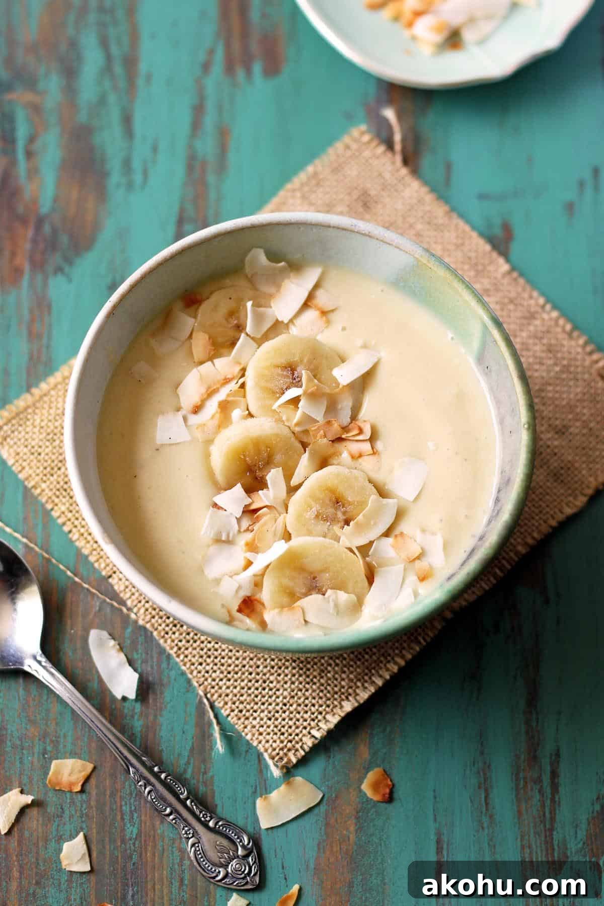 Pina colada smoothie bowl on a green table top.