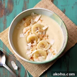 Pina colada smoothie bowl on a green table top.