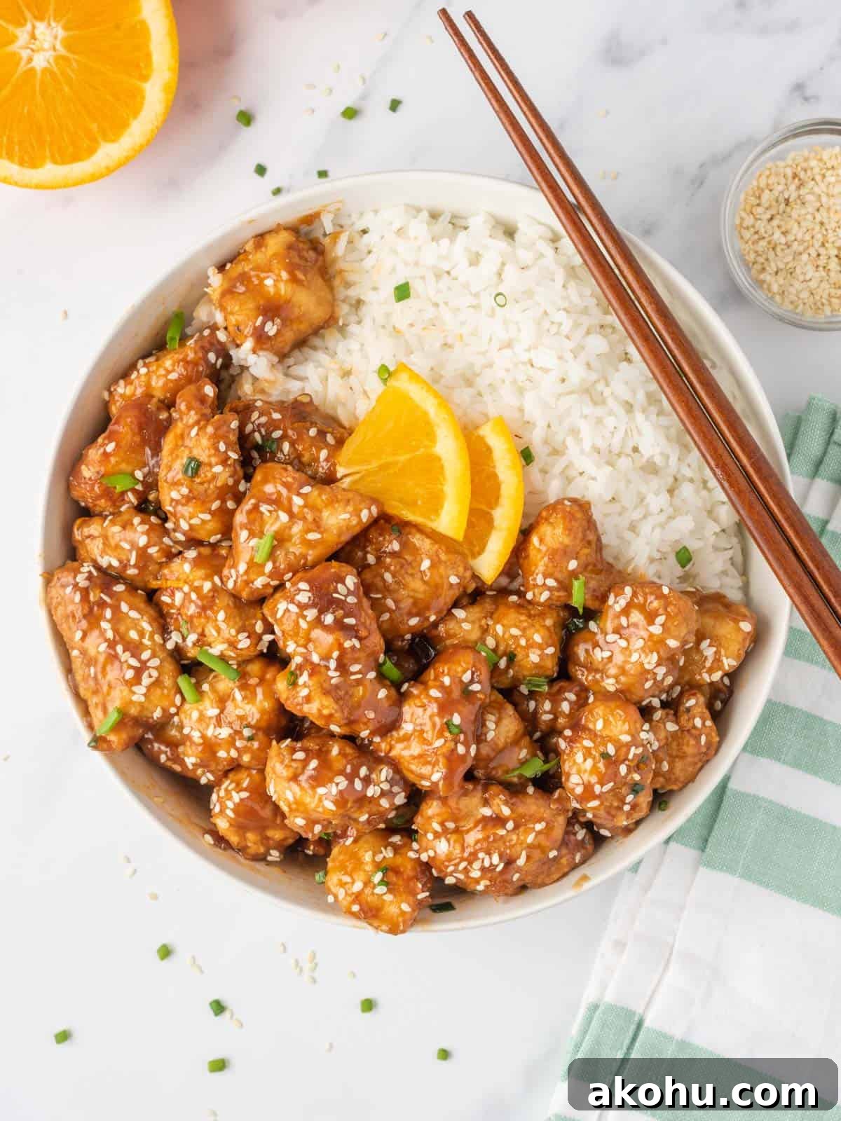 A bowl of crispy chicken in air fryer served with rice and chopsticks.