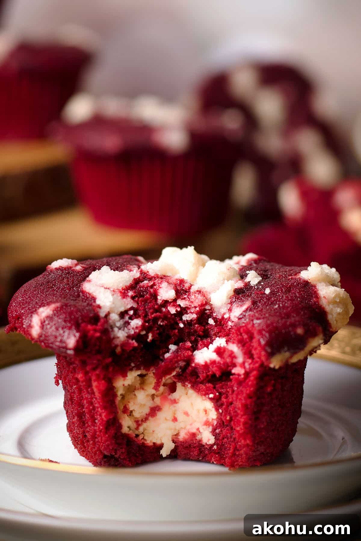 Red Velvet Muffins Filled with Cream Cheese Swirl 2 A red velvet muffin that's been broken in half to reveal the cream cheese filling in the center of the muffin.