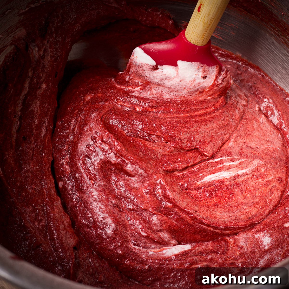 Red Velvet Muffins Filled with Cream Cheese Swirl 14 Using a rubber spatula to gently fold whipped cream into red velvet muffin batter.