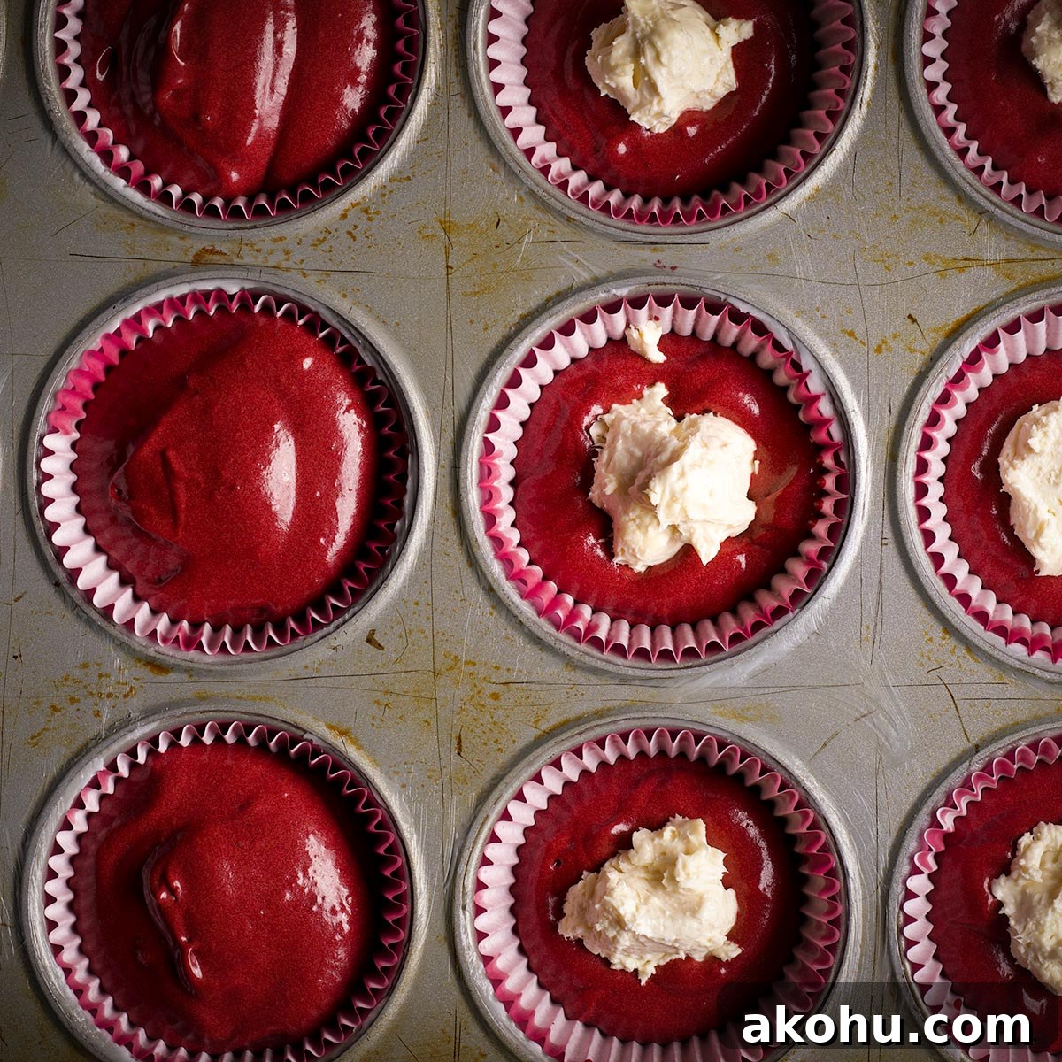 Red Velvet Muffins Filled with Cream Cheese Swirl 15 A muffin tin lined with paper liners and filled with red velvet muffin batter.