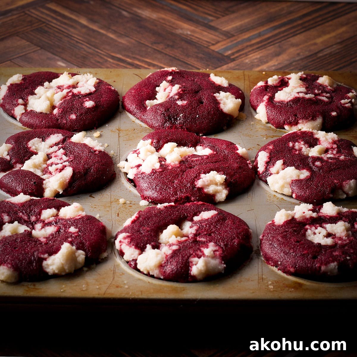 Red Velvet Muffins Filled with Cream Cheese Swirl 17 A freshly baked pan of red velvet muffins with a crumb topping.