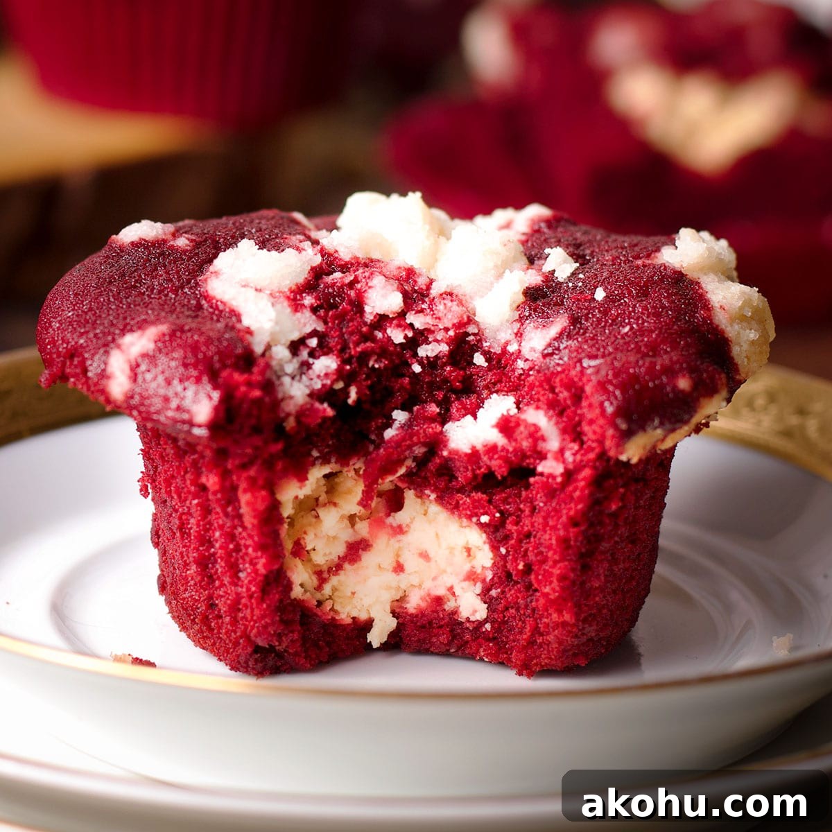 Red Velvet Muffins Filled with Cream Cheese Swirl 18 A red velvet muffin that's been broken in half to reveal the cream cheese filling in the center of the muffin.