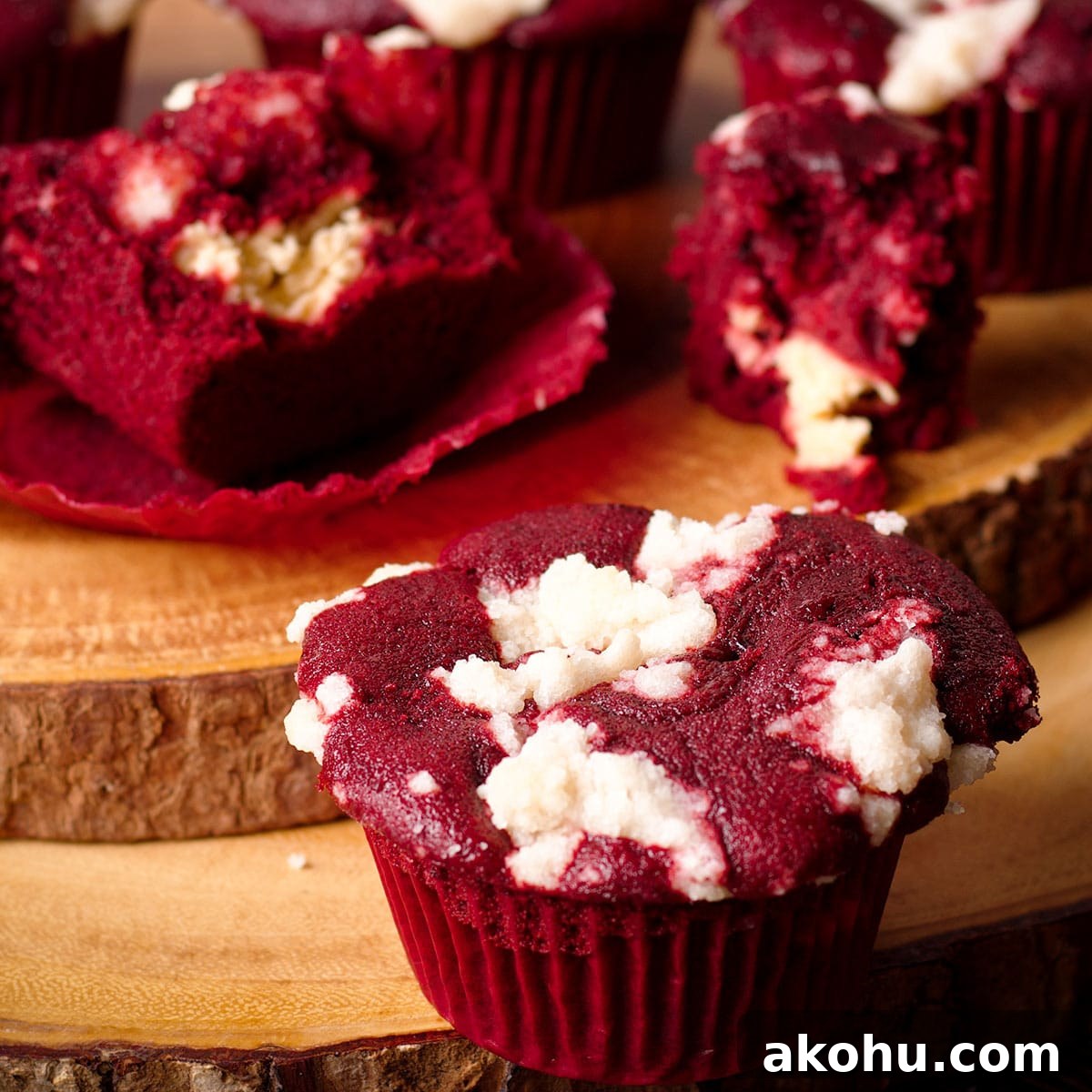 Red Velvet Muffins Filled with Cream Cheese Swirl 23 Several red velvet muffins with cream cheese filling and crumb topping on a wood serving board.