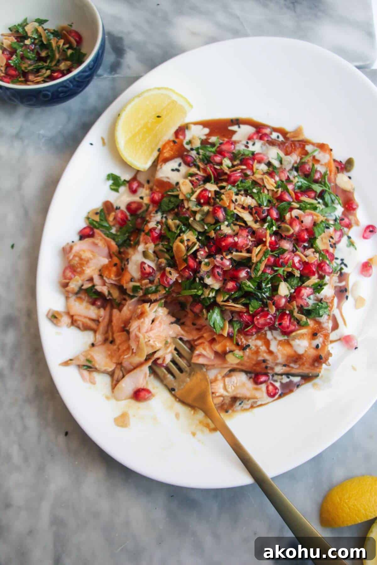 Maple miso glazed salmon fillet with pomegranate almond salsa, with lemon wedges on the side.
