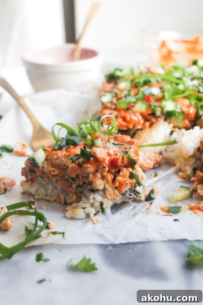 Close up of a piece of salmon sushi bake, with the rest of the bake in the background.