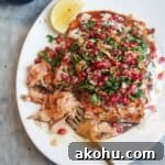 Maple miso glazed salmon fillet with pomegranate almond salsa, with lemon wedges on the side.
