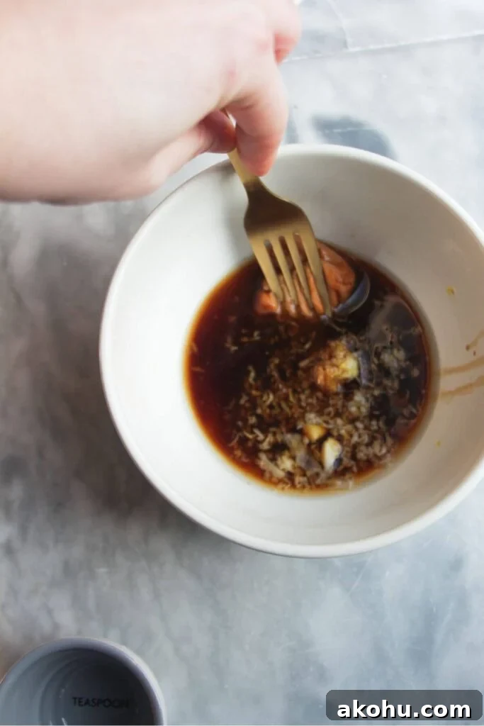Gold fork mixing maple miso glaze in a small white bowl.