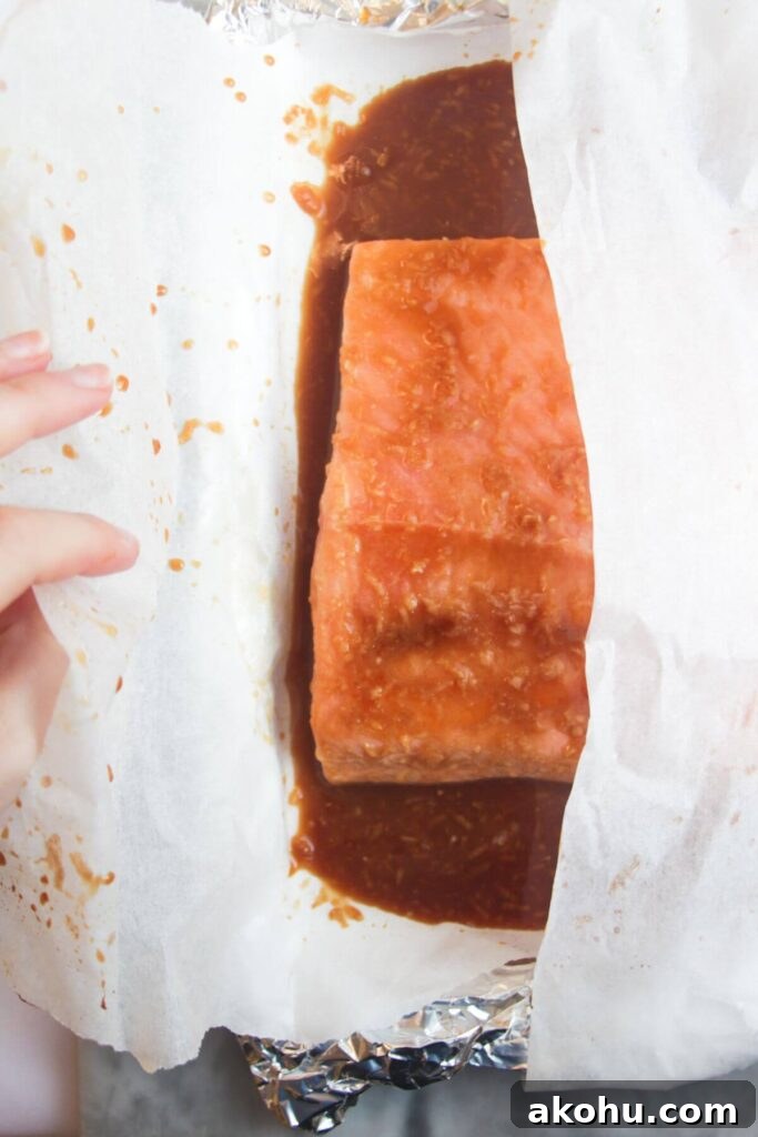 Hand wrapping maple miso glazed salmon fillet in baking paper.