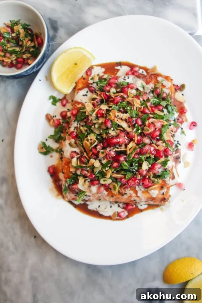 Maple miso glazed salmon fillet with pomegranate almond salsa, with lemon wedges on the side.