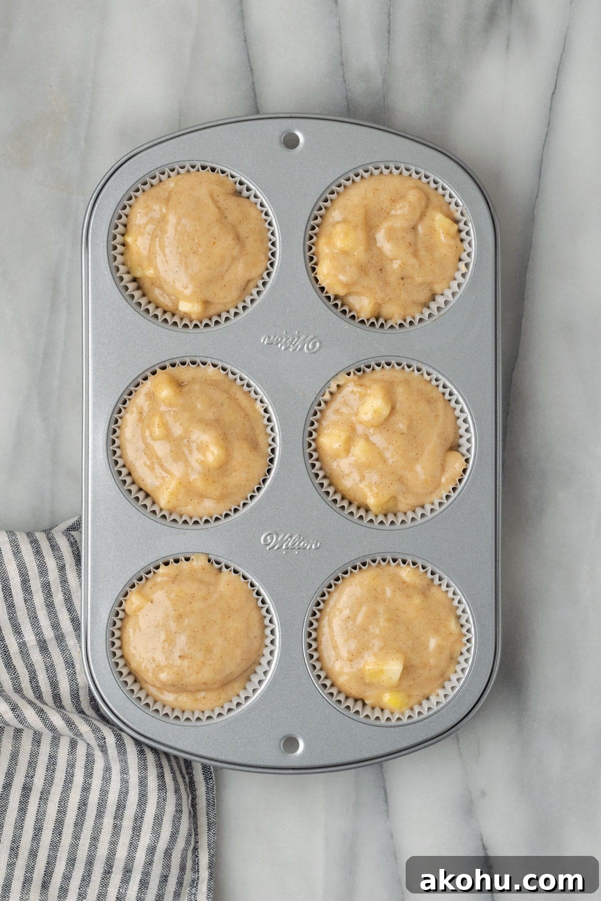 Apple Banana Muffins Recipe for Moist, Fluffy Bites 11 A six cup muffin tin filled with unbaked apple banana muffin batter.