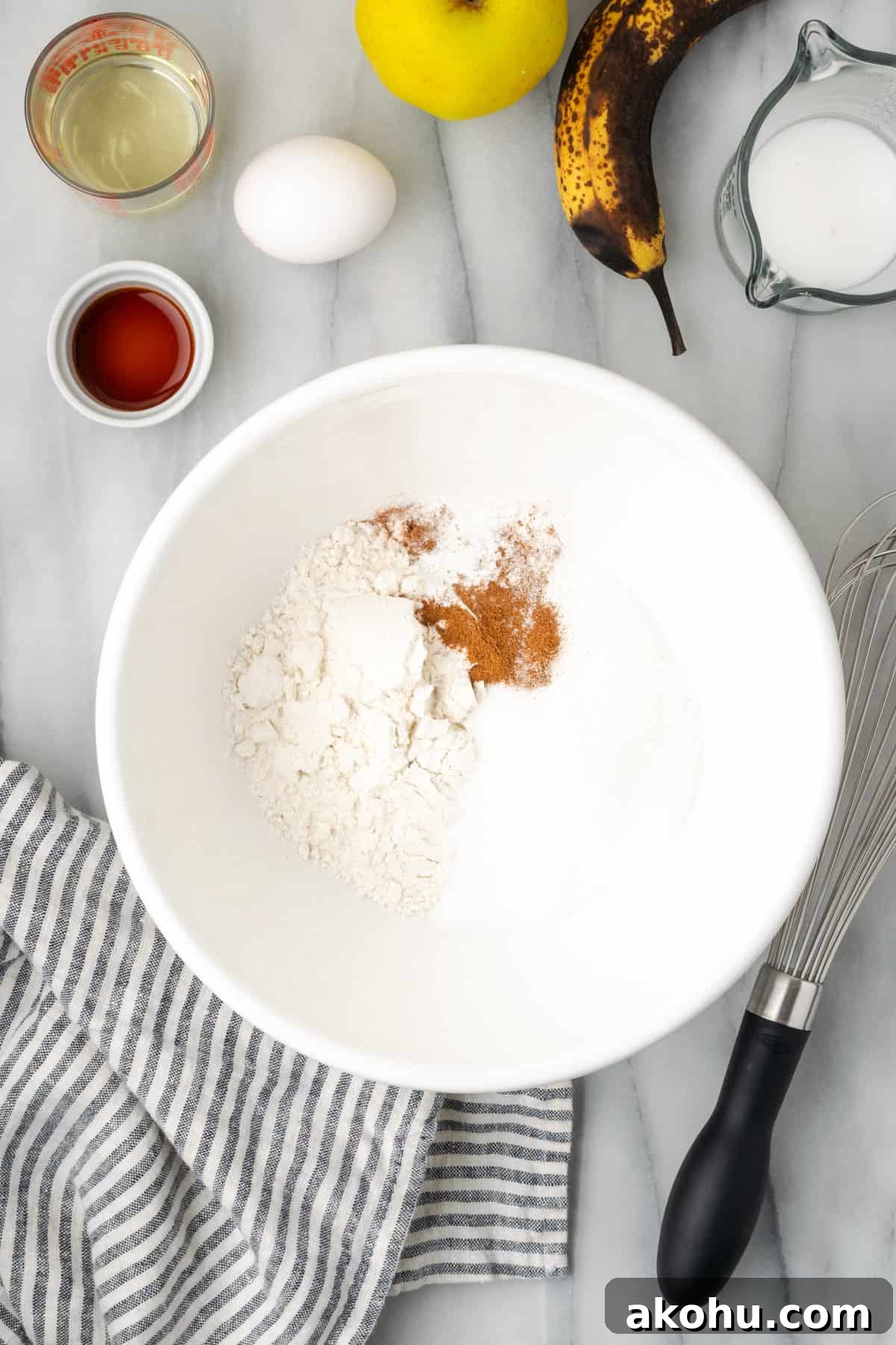 Apple Banana Muffins Recipe for Moist, Fluffy Bites 4 Gluten free flour, sugar, baking powder, salt and apple pie spice combined in a large white bowl.