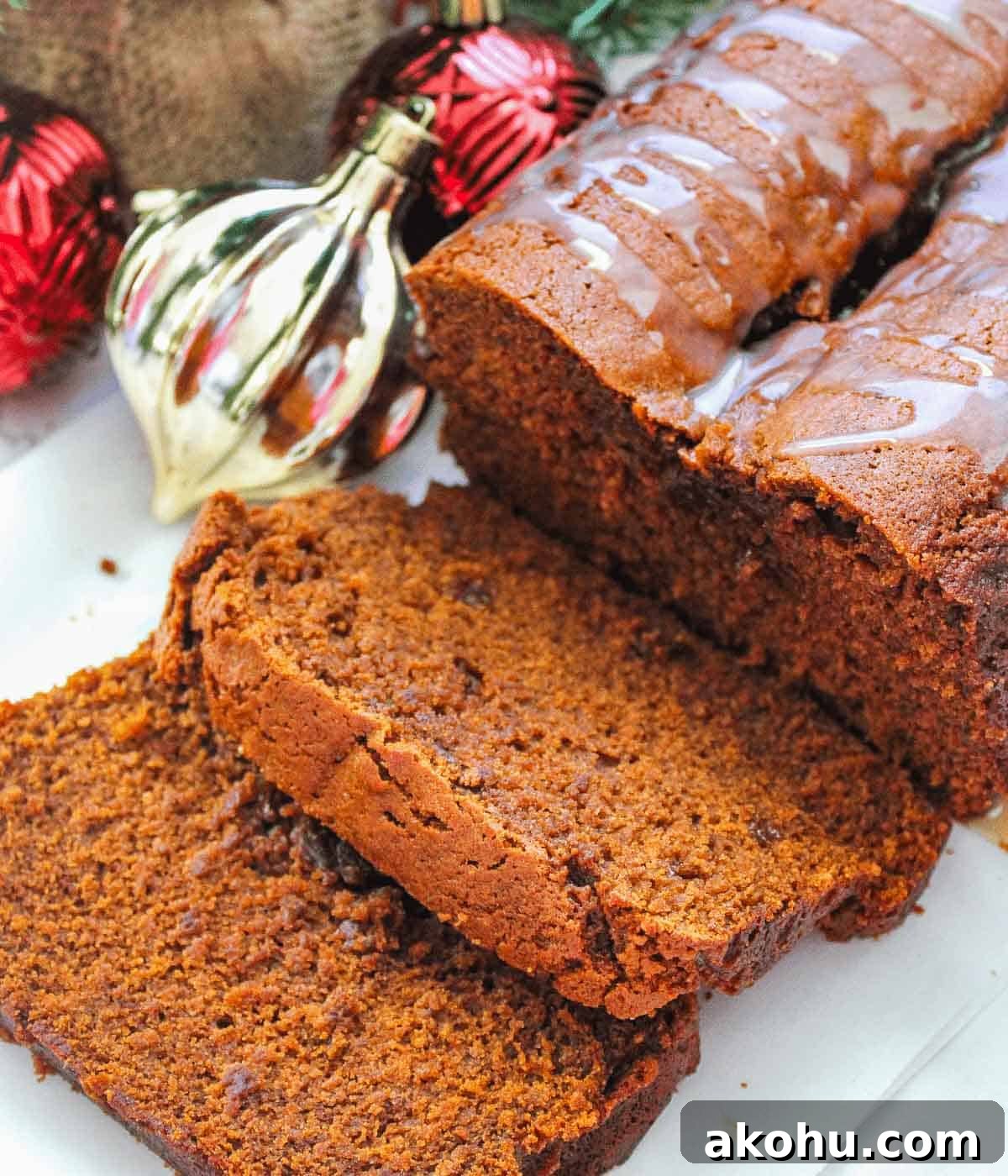 Gingerbread loaf cut into slices surrounded my christmas decorations. 