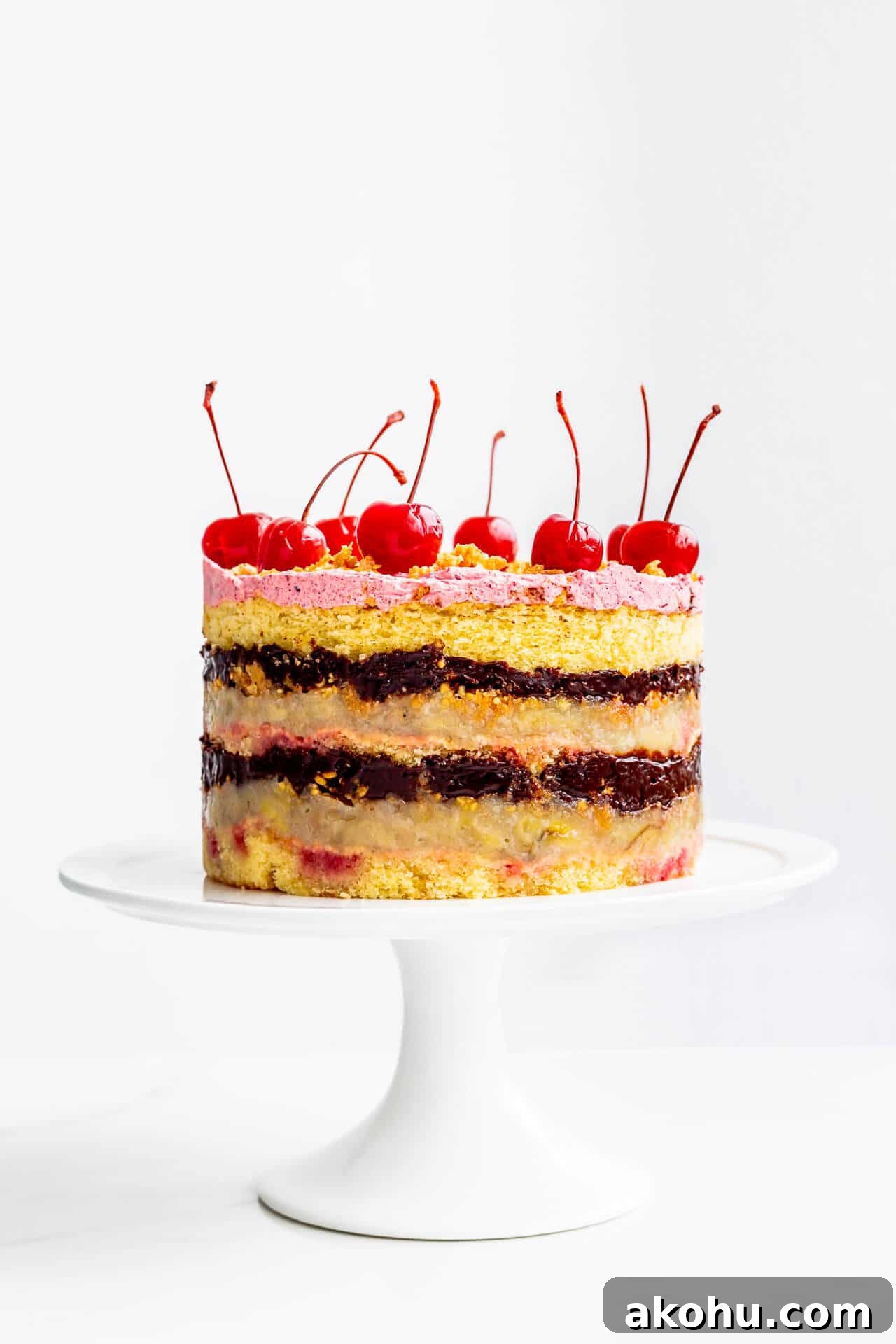Banana split layer cake topped with maraschino cherries.