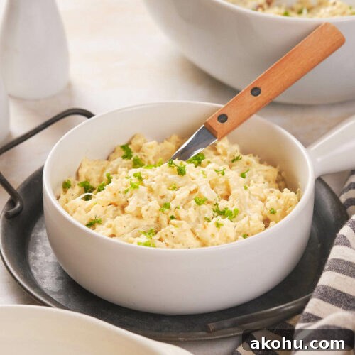 Keto Cauliflower Mac and Cheese: 4-Step Low-Carb Recipe 11 A white bowl filled with scrambled cauliflower garnished with chopped herbs.