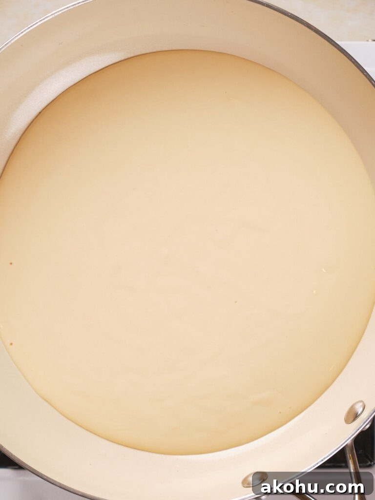 Keto Cauliflower Mac and Cheese: 4-Step Low-Carb Recipe 4 A close-up view of a creamy liquid in a white frying pan.