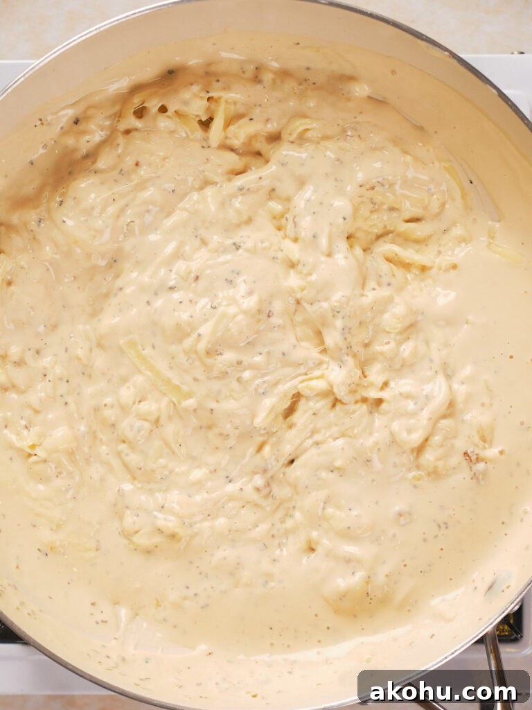 Keto Cauliflower Mac and Cheese: 4-Step Low-Carb Recipe 5 A close-up of a pan filled with creamy, light beige sauce, with visible herbs and spices.