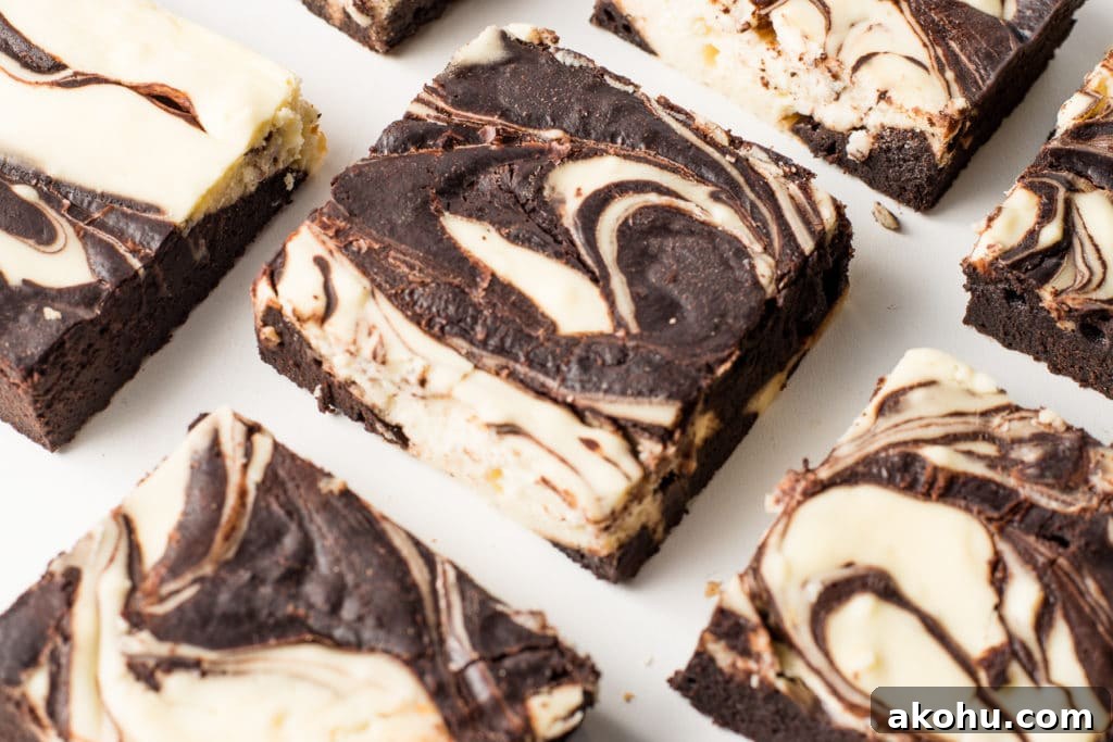 Swirled cheesecake brownies on a bright white background.