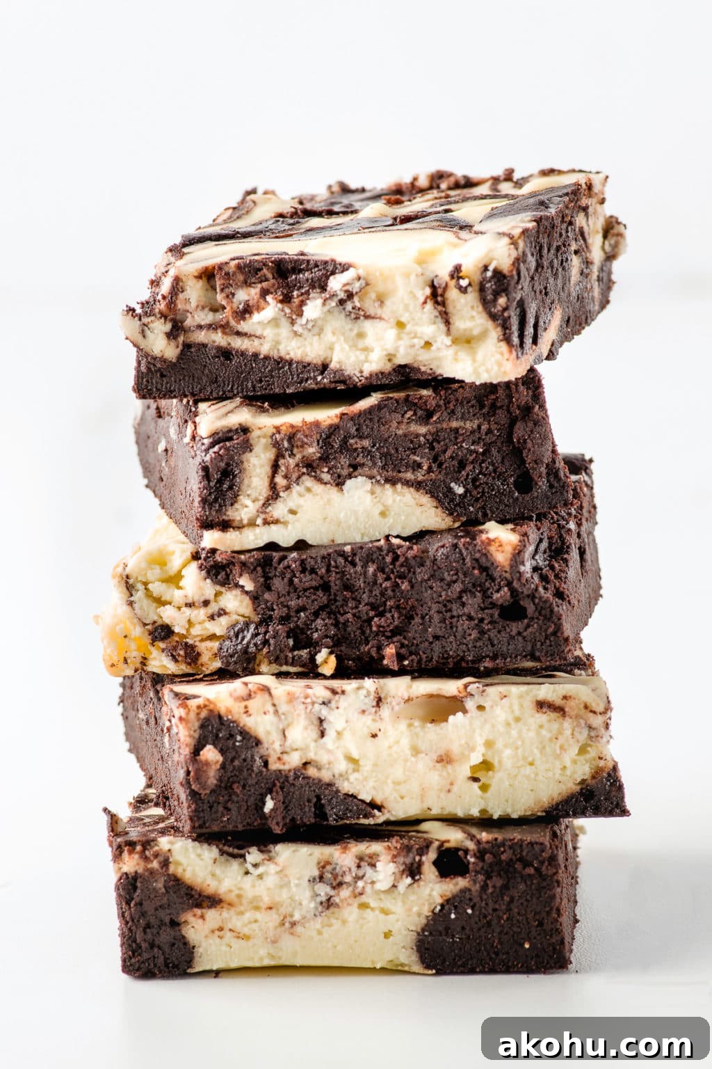 A stack of keto cheesecake brownies against a bright white background.