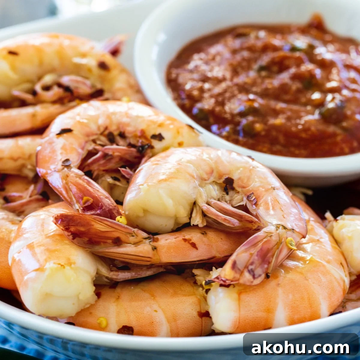 Cooked Shrimp on plate with bowl of cocktail sauce.