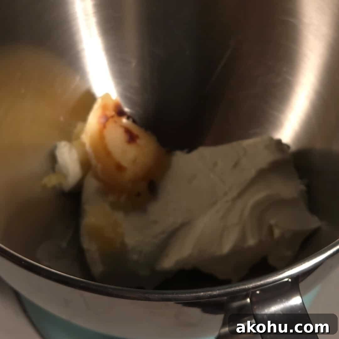 Cream cheese and browned butter in a mixing bowl before whipping into browned butter cream cheese frosting.