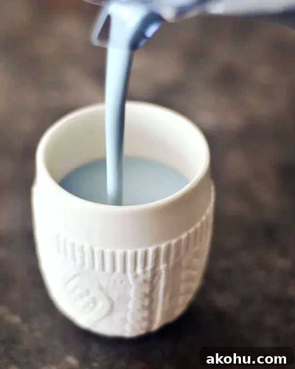 pale blue vanilla mint cashew milk being poured into a white mug