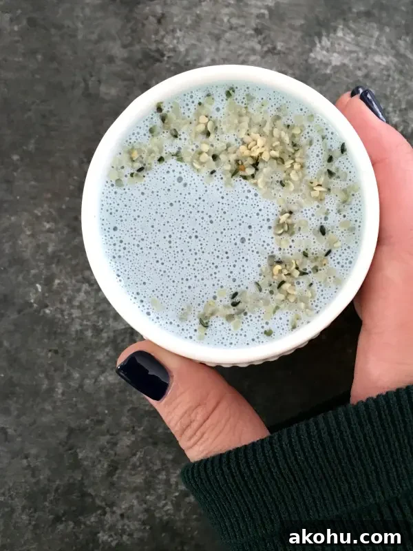 overhead view of pale blue vanilla mint cashew milk in a white mug, garnished with hemp seeds
