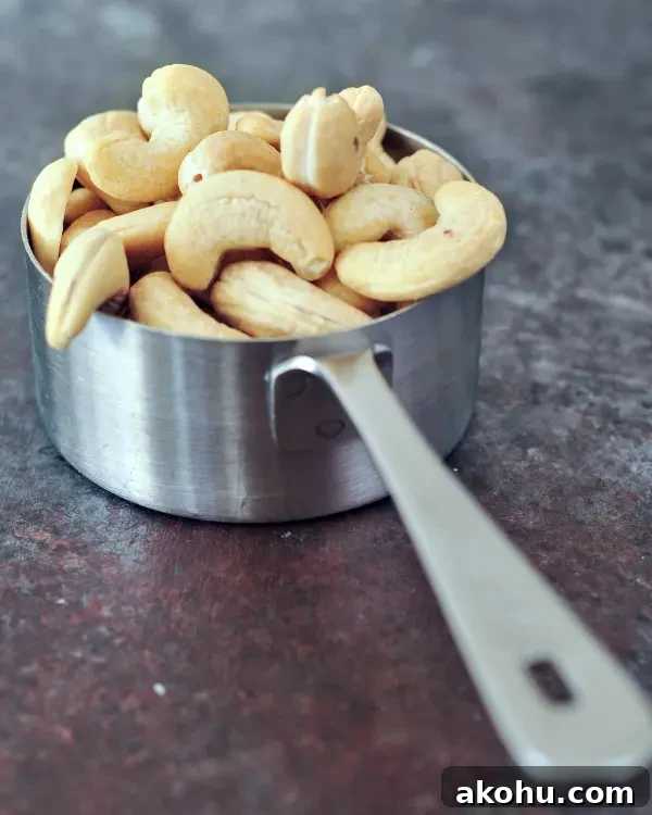 a stainless steel measuring cup filled with cashews