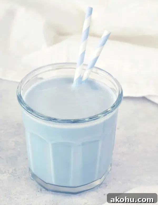 pale blue vanilla mint cashew milk in a clear glass with blue and white striped paper straws