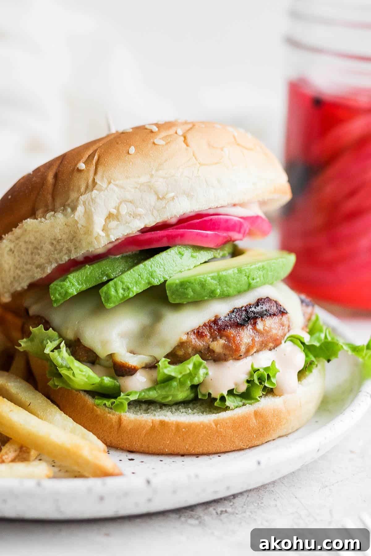 An easy turkey avocado burger on a plate with all the toppings.
