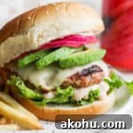 Avocado turkey burger on a bun on a plate with fried.