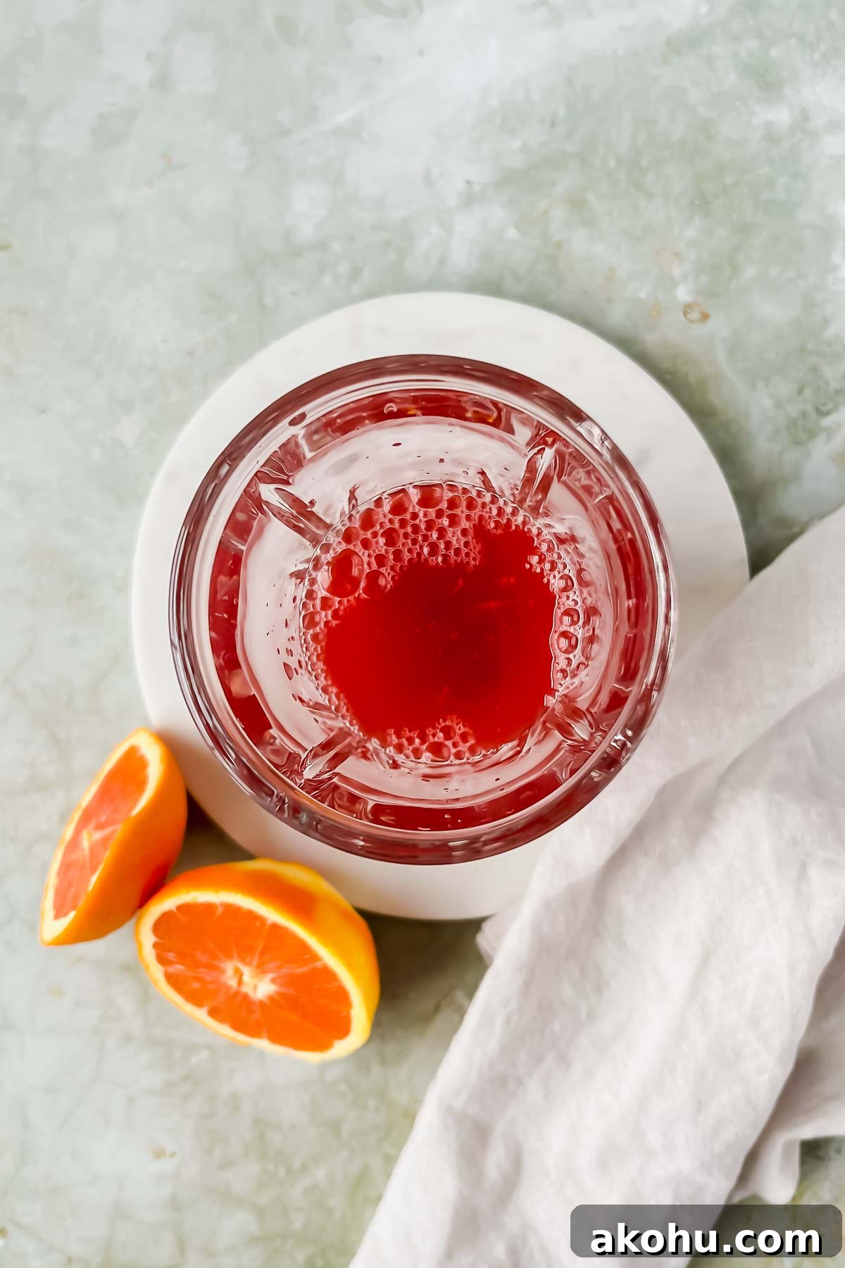ariel view of cranberry whiskey sour in glass shaker on green background.