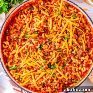 The finished sloppy joe pasta in a pan garnished with cheddar chese and parsly.