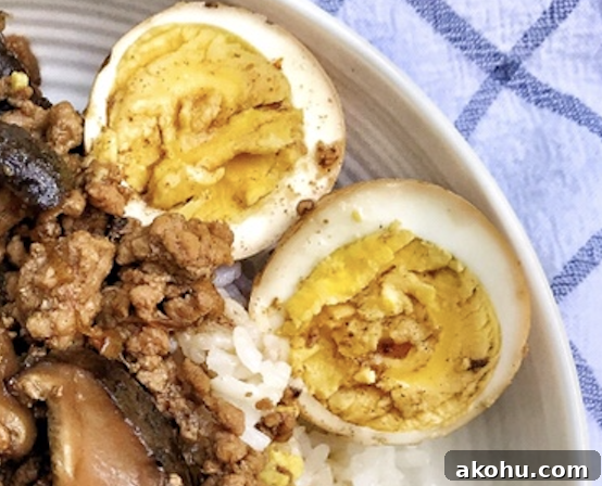 A hard boiled egg split in half on the side of the plate of ground pork and rice.