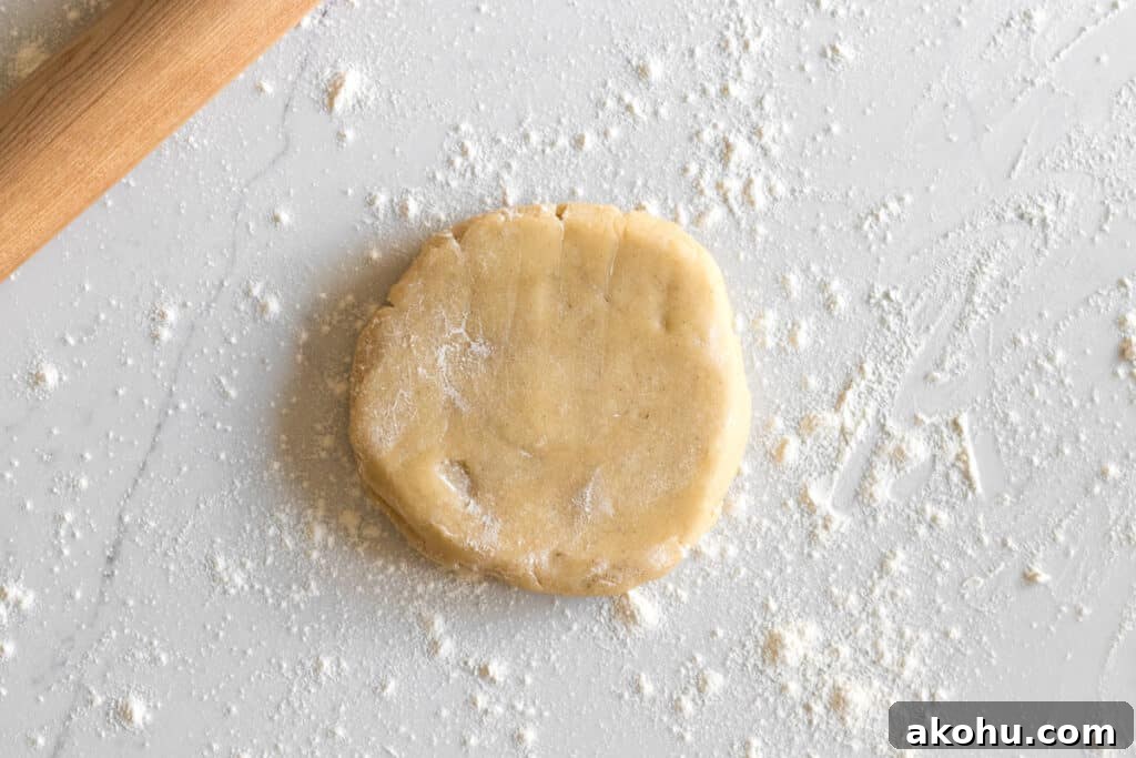 disc of sugar cookie dough with wood rolling pin