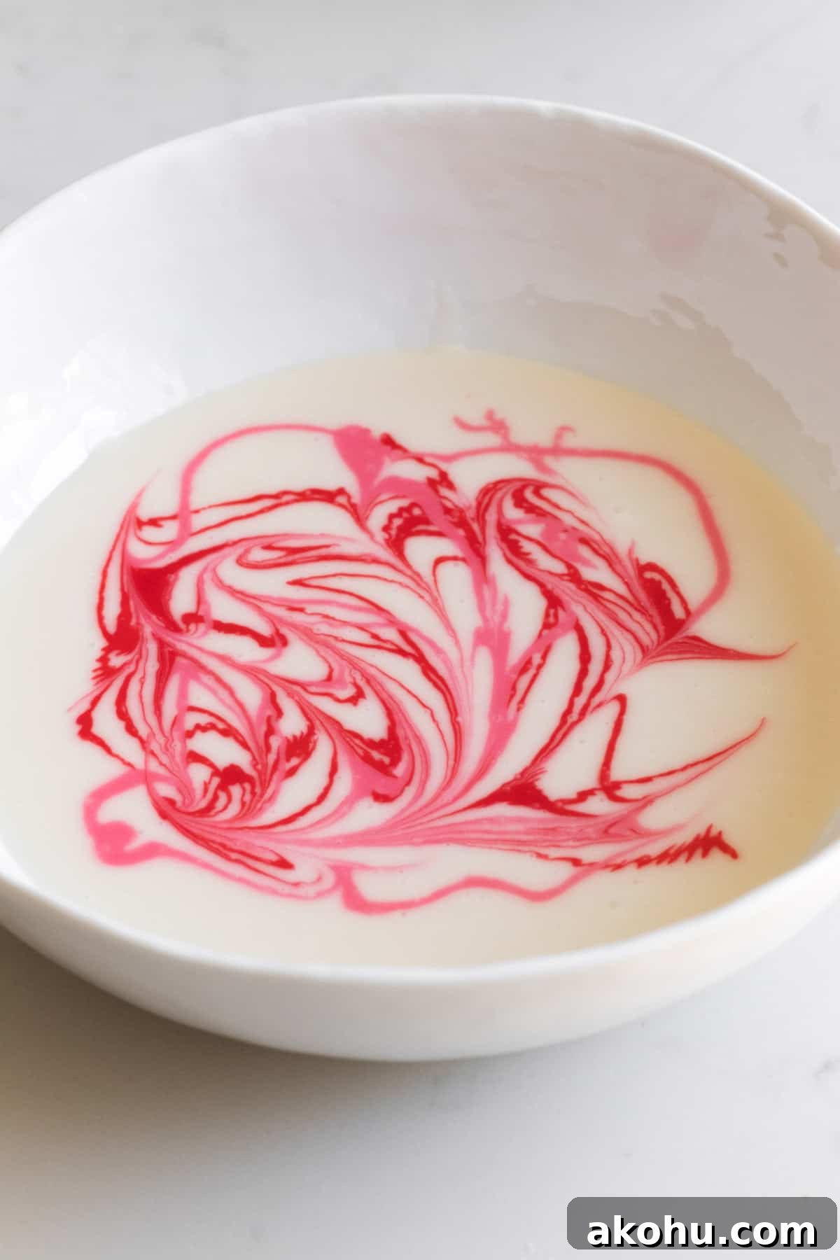 bowl of white icing with pink and red swirls in it