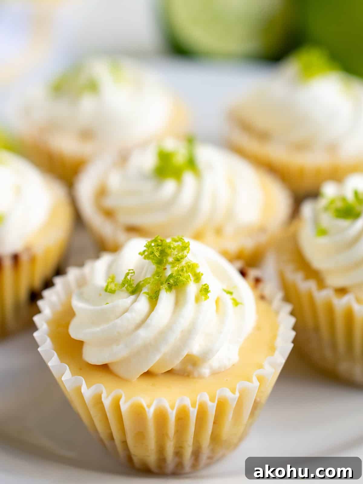 Close up of a mini key lime pie on a white plate filled with several mini pies.