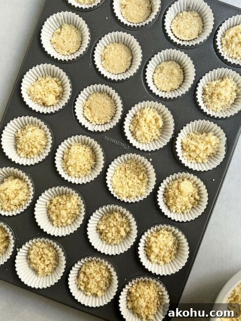Mini cupcake holder pan filled with white liners filled with macadamia crust for mini key lime pies.