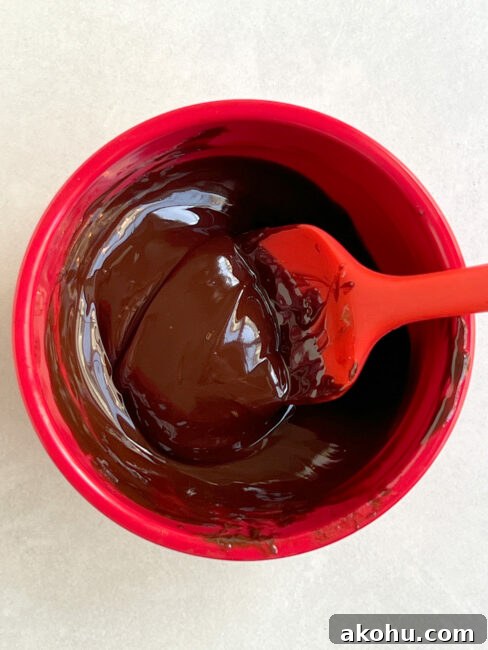 Chocolate mixture glistening and ready to spread on the mini key lime pie crusts.