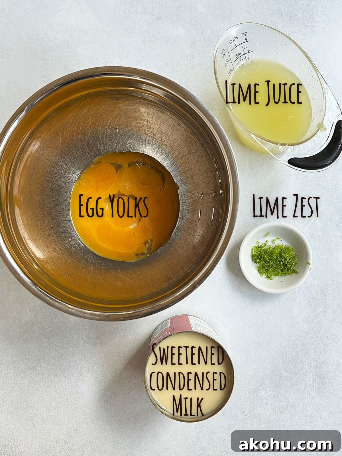 Ingredient shot for mini key lime pies showing filling ingredients - egg yolks, lime zest, lime juice and sweetened condensed milk.