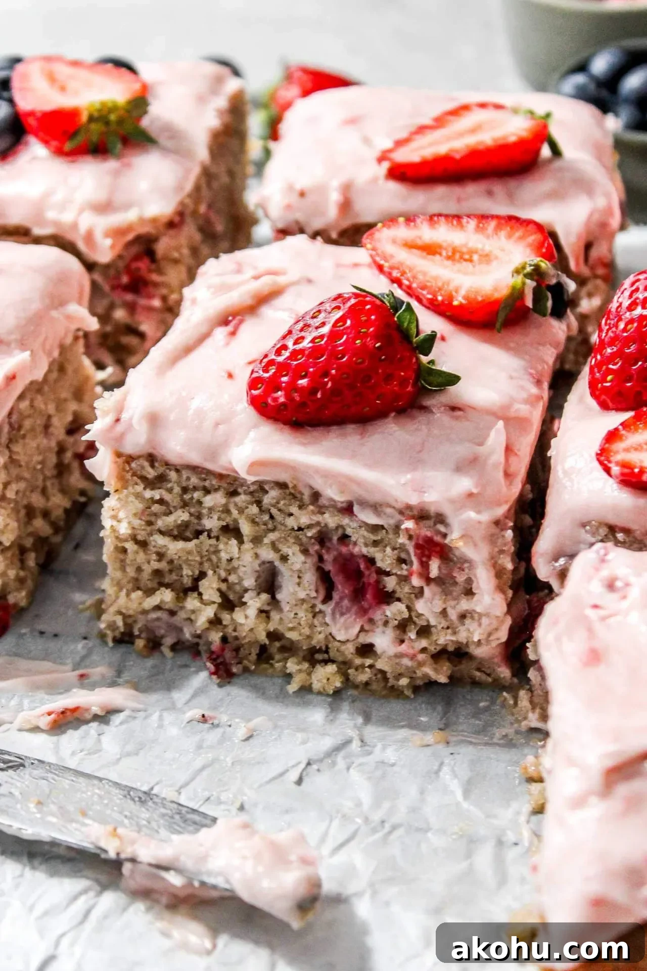 sliced strawberry sheet cake on parchment lined wire rack decorated with fresh strawberries and blueberries (5)